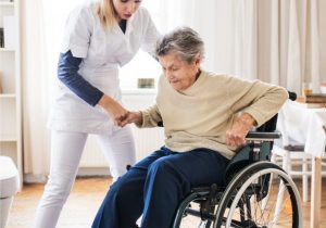 Pflegekraft hilft pflegebedürftiger Seniorin